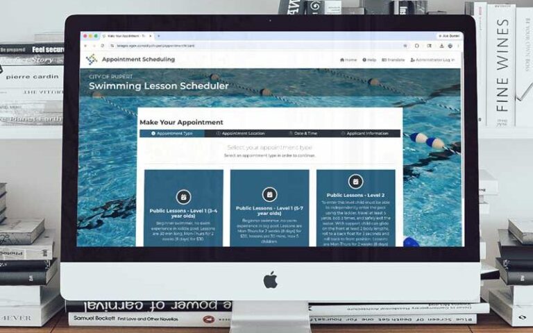 City or Rupert Swimming Lesson Scheduling site on computer with books in background