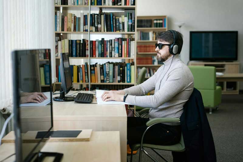 man sitting at computer using assistive technology