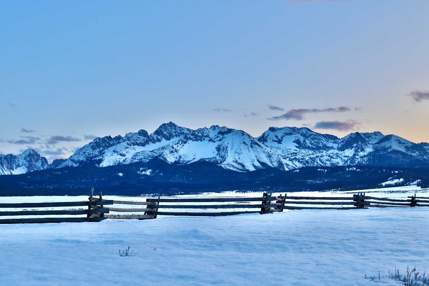 snowy sawtooth mountains with fence in foreground