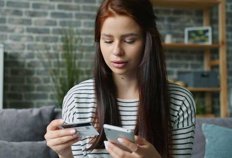 woman holding credit card and cell phone